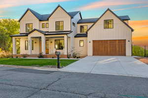 Modern farmhouse featuring a porch, driveway, a standing seam roof, board and batten siding, and a metal roof