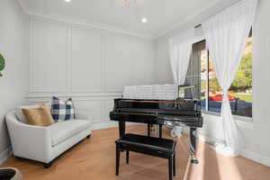 Sitting room with a decorative wall, recessed lighting, wood finished floors, and ornamental molding