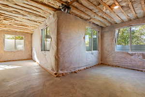 Unfurnished room with unfinished concrete flooring