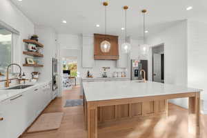 Kitchen featuring white cabinetry, stainless steel appliances, light stone counters, light wood-type flooring, and recessed lighting