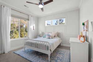 Carpeted bedroom with crown molding, a decorative wall, and a ceiling fan