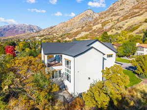 View of side of property with a balcony, a mountain view, and a shingled roof