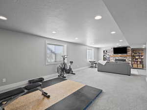Exercise area with a textured ceiling, carpet floors, a fireplace, and recessed lighting
