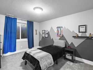Bedroom with light carpet and a textured ceiling