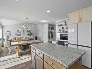 Kitchen featuring light brown cabinets, freestanding refrigerator, a kitchen island, dark wood-type flooring, and open floor plan