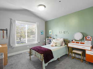 Carpeted bedroom featuring vaulted ceiling and a textured ceiling