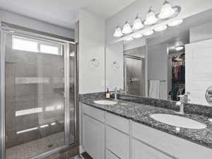 Full bathroom featuring double vanity, a walk in closet, and a shower stall
