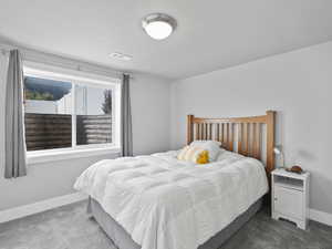 Carpeted bedroom featuring baseboards and a textured ceiling