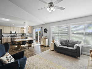 Living room with vaulted ceiling, ceiling fan, dark wood-type flooring, and a textured ceiling