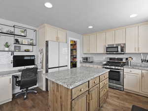 Kitchen featuring light brown cabinetry, stainless steel appliances, dark wood-style flooring, light stone counters, and recessed lighting