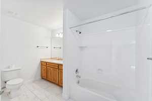 Bathroom with washtub / shower combination, light marble finish flooring, vanity, and a textured ceiling