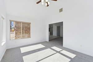 Unfurnished room featuring carpet flooring, high vaulted ceiling, and ceiling fan