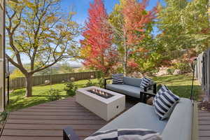 Wooden deck with a fenced backyard and an outdoor living space with a fire pit