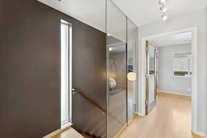 Hallway featuring an upstairs landing and light wood-style flooring