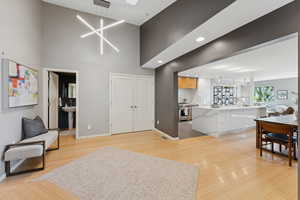 Living room featuring a high ceiling, light wood-style floors, a chandelier, and recessed lighting