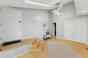 Entrance foyer featuring a skylight, a high ceiling, light wood finished floors, and a chandelier
