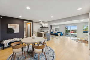 Dining space with a bar, light wood-style flooring, and recessed lighting