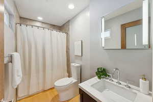 Full bath with curtained shower, vanity, light wood-style floors, and recessed lighting