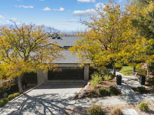View of front of house featuring a shingled roof, a garage, concrete driveway, and a mountain view