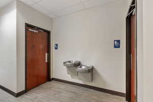 Hall with light wood-style flooring and a drop ceiling