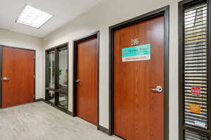 Corridor featuring a paneled ceiling and light wood-style floors