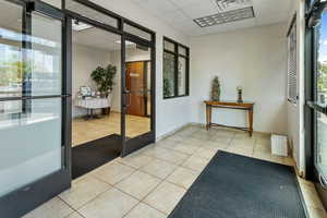 Doorway featuring a paneled ceiling, tile patterned flooring, and french doors