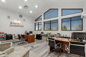 Office area with high vaulted ceiling, a wall mounted air conditioner, and recessed lighting