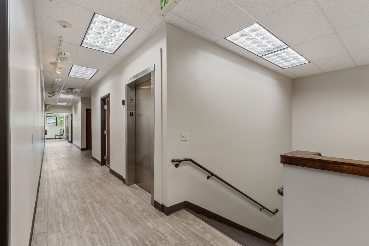 Hall with a drop ceiling, an upstairs landing, elevator, and light wood-style flooring