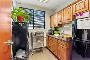 Kitchen featuring a drop ceiling, black appliances, and brown cabinetry