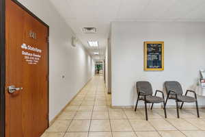 Corridor featuring a paneled ceiling and light tile patterned floors