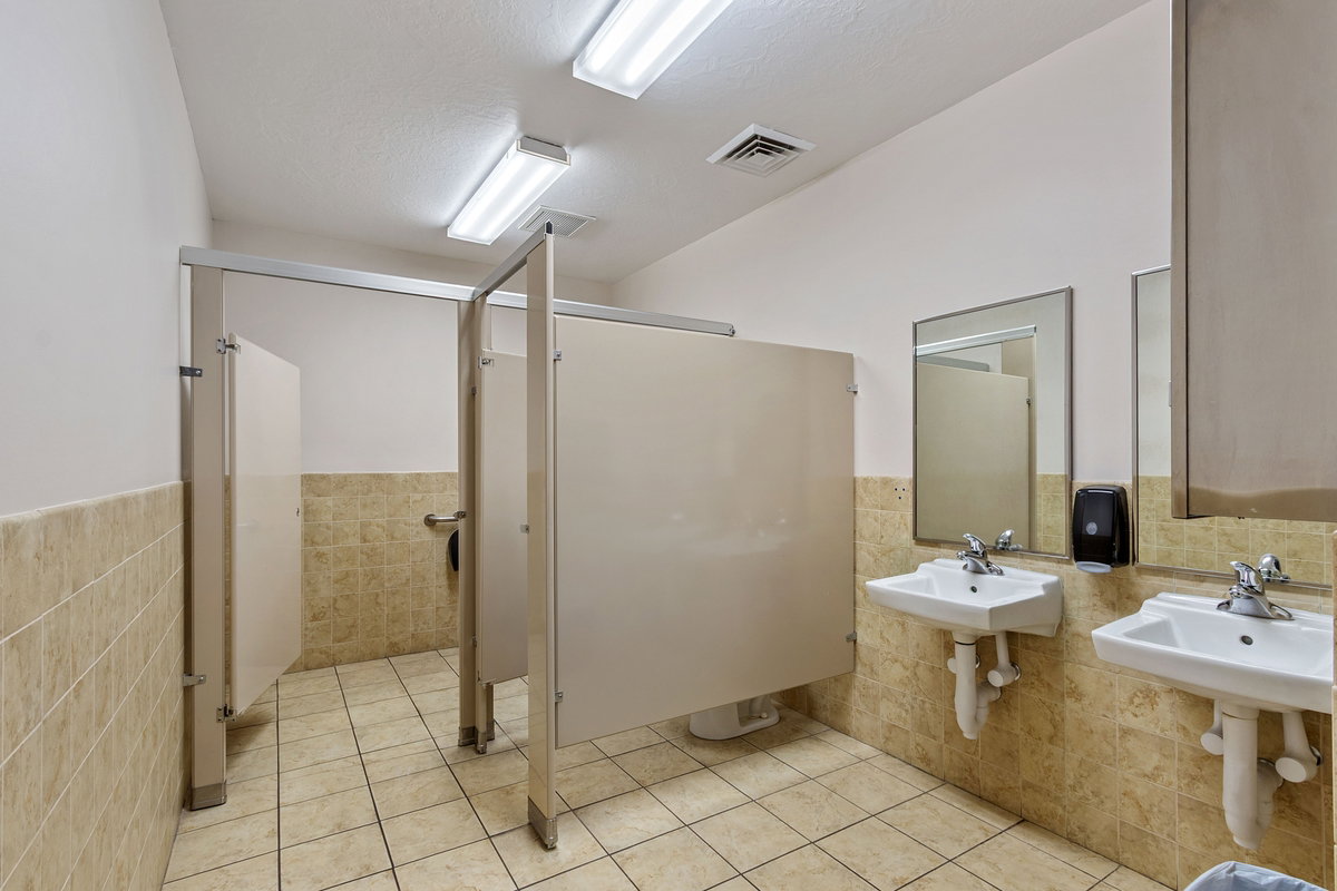 Full bath with tile walls, a stall shower, a wainscoted wall, and light tile patterned floors