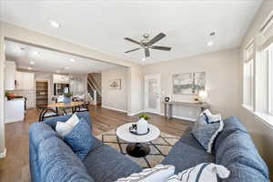 Living area featuring stairway, wood finished floors, recessed lighting, a chandelier, and a ceiling fan