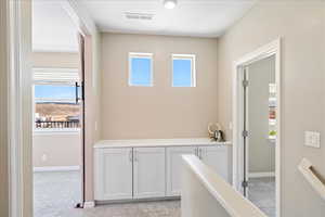Hallway featuring light carpet and plenty of natural light
