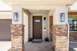 Entrance to property featuring a porch, stucco siding, and a garage