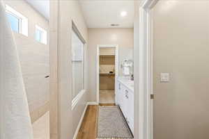 Full bathroom featuring a spacious closet, double vanity, light wood-style floors, and walk in shower