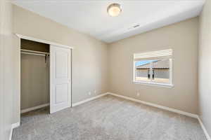 Unfurnished bedroom with light colored carpet and a closet