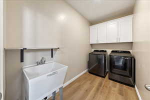Laundry room featuring light wood-style flooring, washer and dryer, and cabinet space