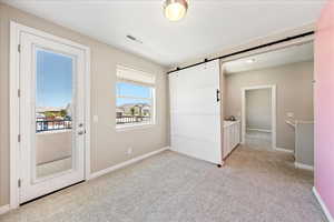 Unfurnished bedroom featuring light carpet and a barn door
