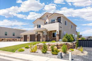View of front of property with a balcony, a garage, stucco siding, concrete driveway, and brick siding