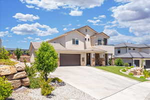 View of front of home with stucco siding, stone siding, driveway, a tile roof, and an attached garage