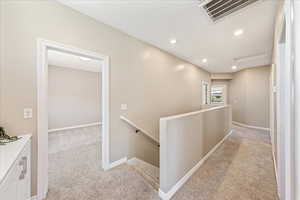 Hall featuring light carpet, an upstairs landing, and recessed lighting