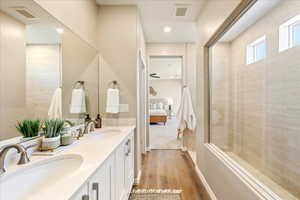 Bathroom featuring double vanity, connected bathroom, light wood-type flooring, recessed lighting, and a shower with shower door