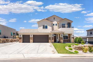 View of front of property featuring a balcony, stucco siding, concrete driveway, a tiled roof, and a front yard