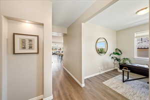 Corridor with light wood finished floors, a desk, and healthy amount of natural light