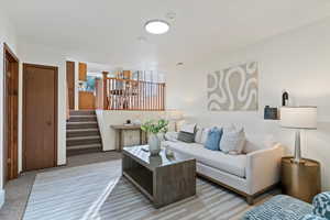 Carpeted living room featuring stairway