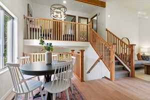 Dining space featuring light wood-type flooring, beam ceiling, stairs, and a chandelier