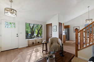Entryway featuring a chandelier, light wood-type flooring, lofted ceiling, and stairs