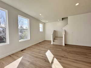 Unfurnished living room featuring stairway, recessed lighting, light wood finished floors, and a textured ceiling