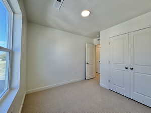 Unfurnished bedroom with light carpet, a textured ceiling, and a closet