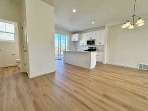Kitchen with white cabinets, open floor plan, decorative light fixtures, a kitchen island with sink, and recessed lighting